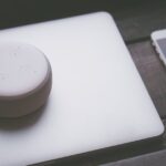 A smart speaker, laptop, and smartphone array representing modern technology lifestyle on a wooden s