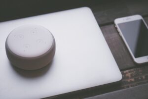 A smart speaker, laptop, and smartphone array representing modern technology lifestyle on a wooden s