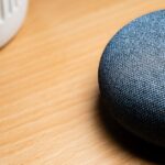 A close-up view of a smart speaker on a wooden table, capturing texture details.